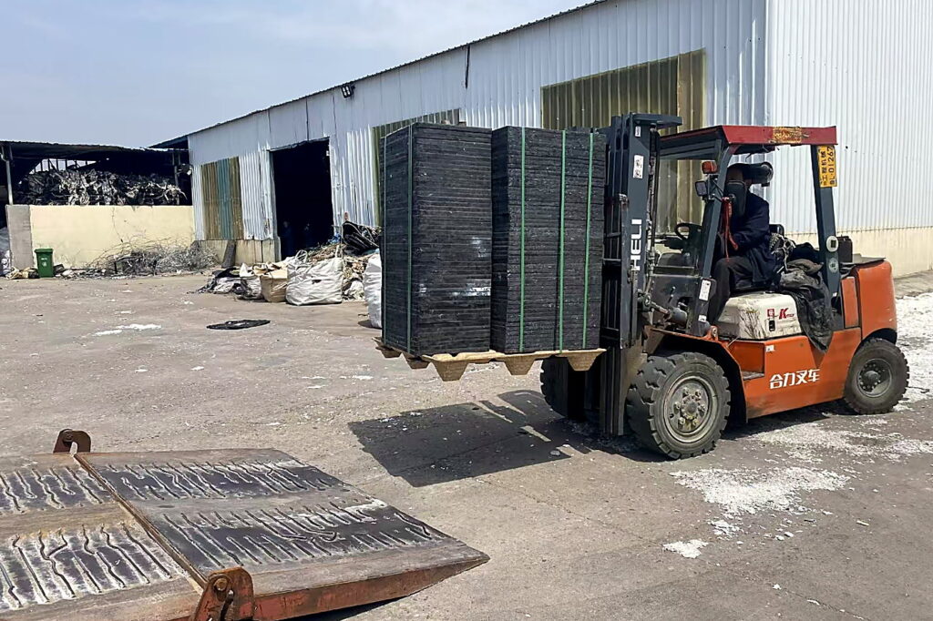 Forklift handling a stack of molded wood pallets in the factory yard